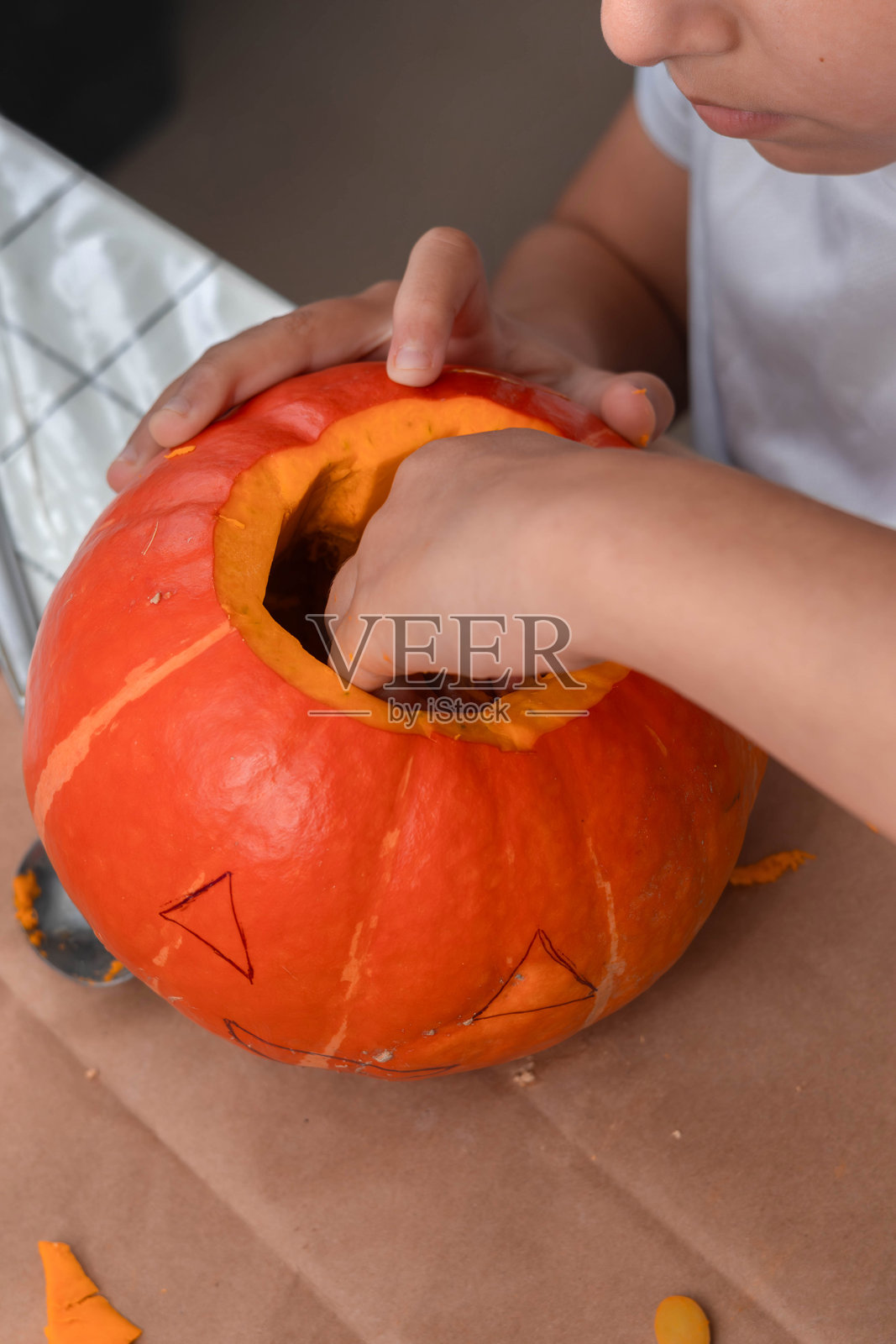 一个孩子正在掏空南瓜的瓤，为雕刻做准备。照片摄影图片