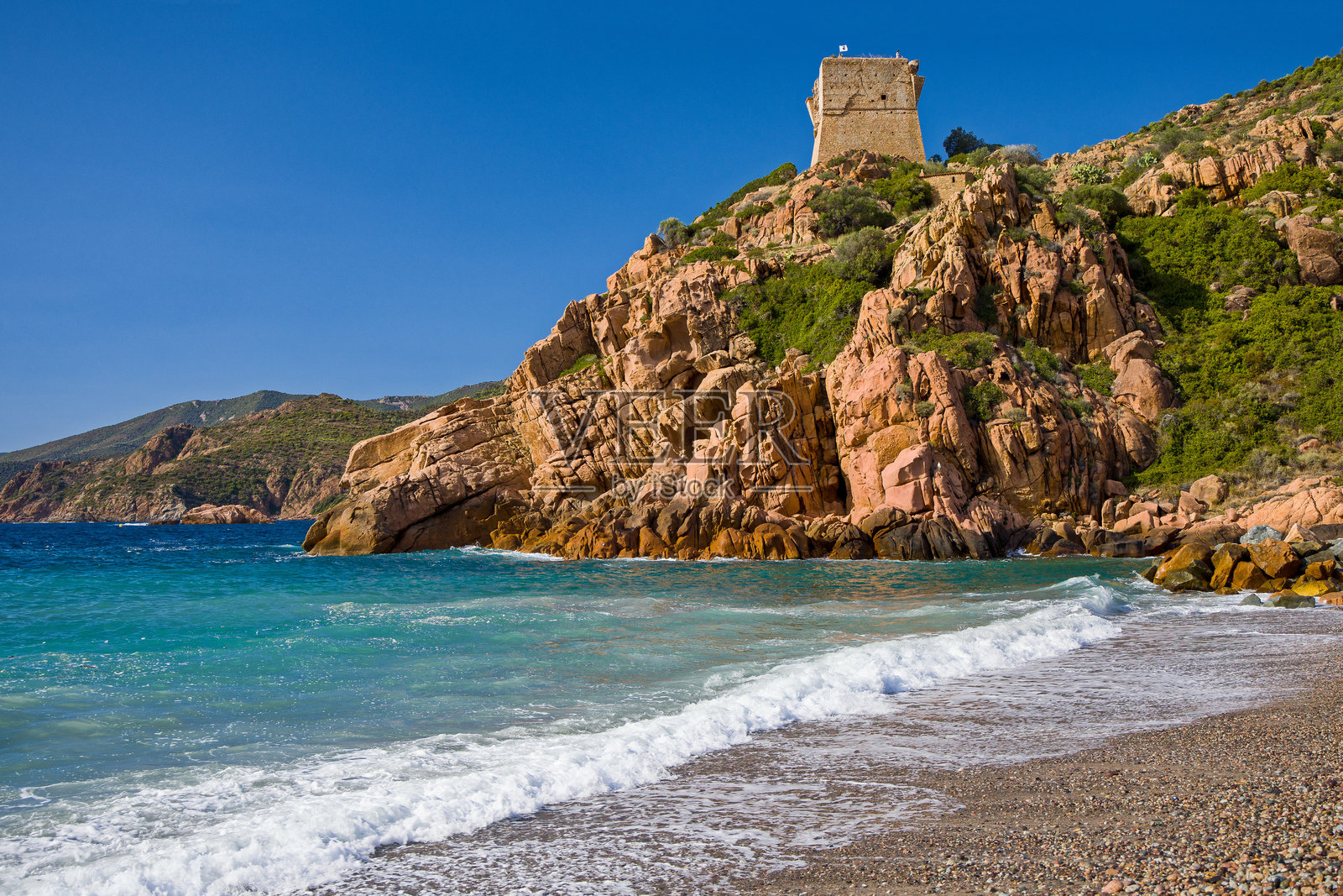 阳光明媚的蓝天下，从海滩和绿松石色的海面上看到的 Porto Ota 红色岩石上的热那亚塔。照片摄影图片