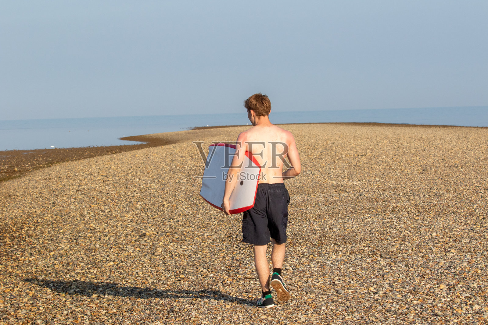 带着冲浪板在海滩上散步照片摄影图片