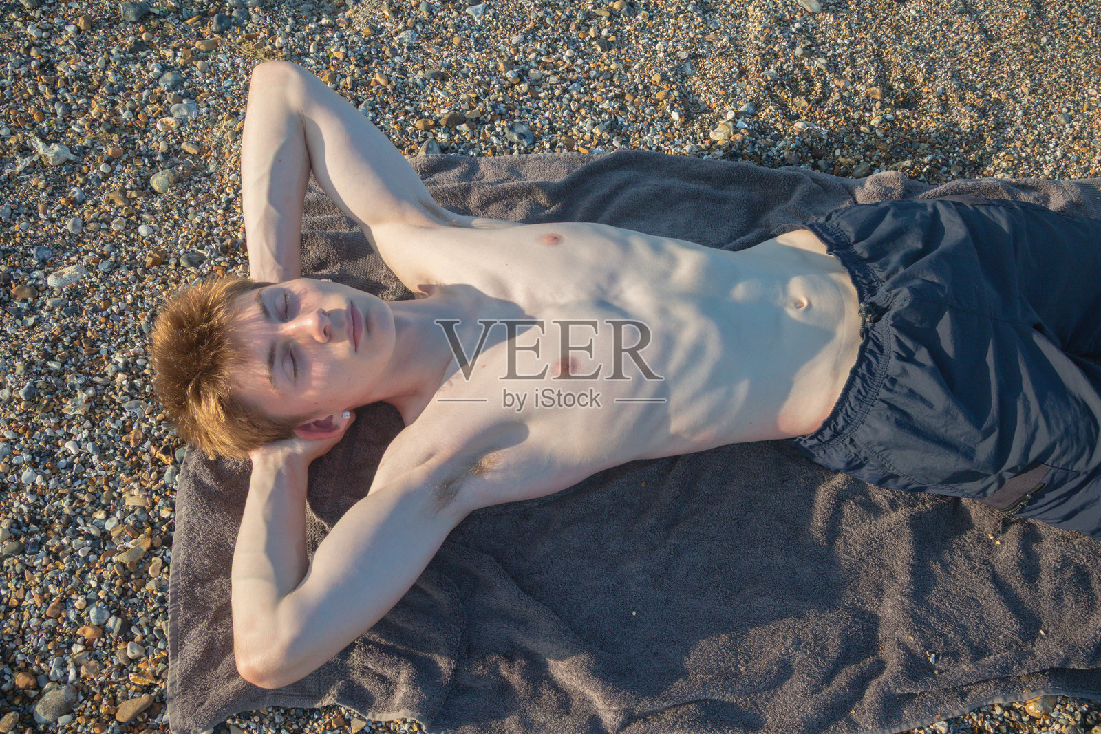 一个少年在海滩上晒太阳照片摄影图片