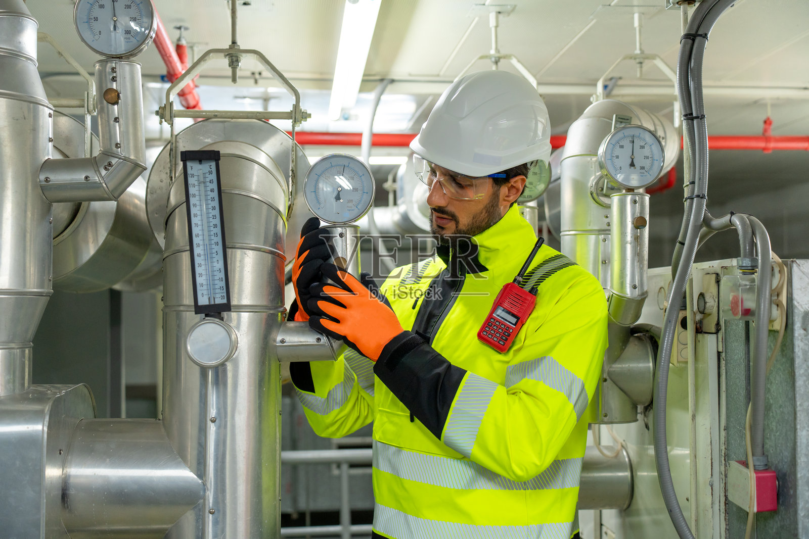 拉丁美洲工程师正在检修压缩机和制冷系统，以确保工业设施内高效的供热和空调。照片摄影图片