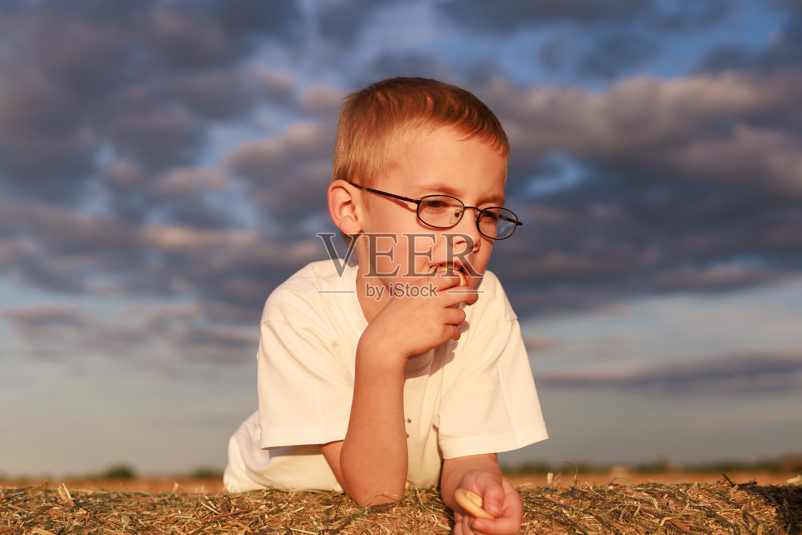 男孩躺在干草堆上照片摄影图片