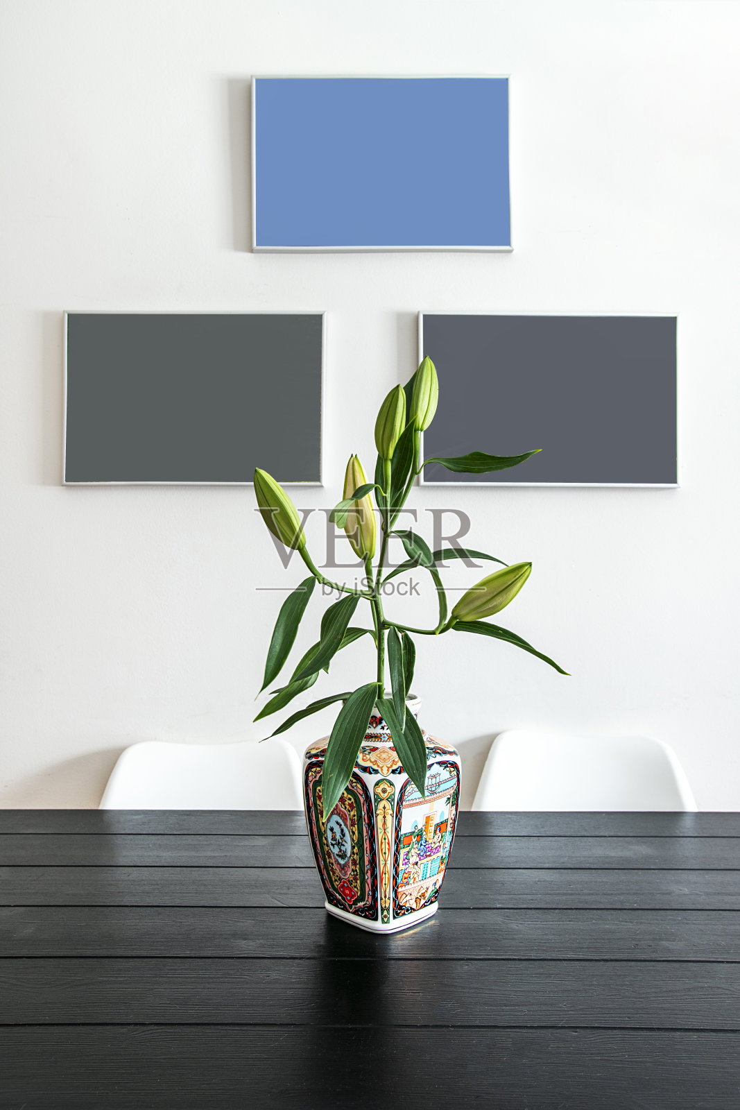 黑木桌中央摆放着一个花瓶，瓶中插着一束含苞待放的花朵。照片摄影图片