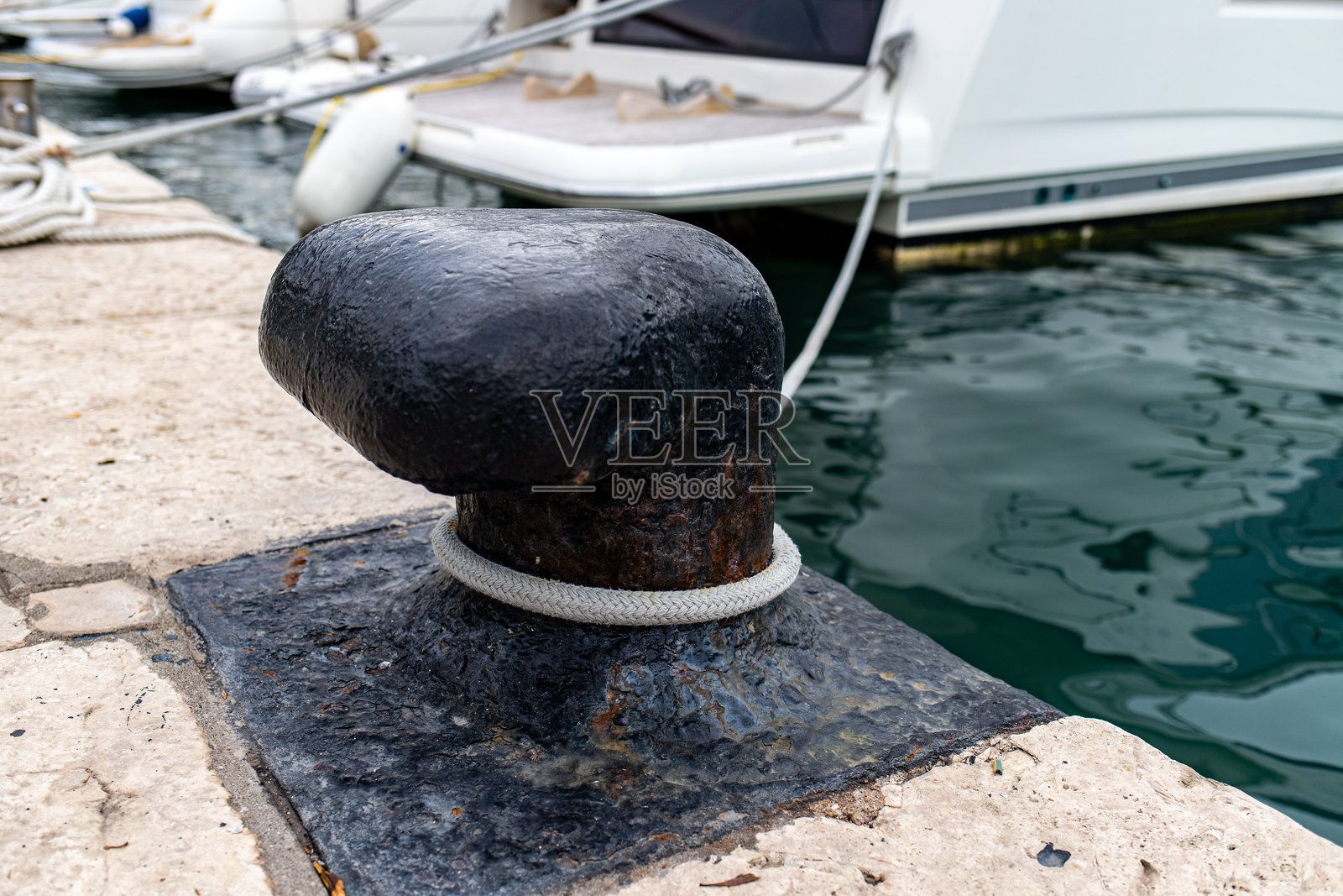 海边石码头上铸铁系船柱的特写照片摄影图片