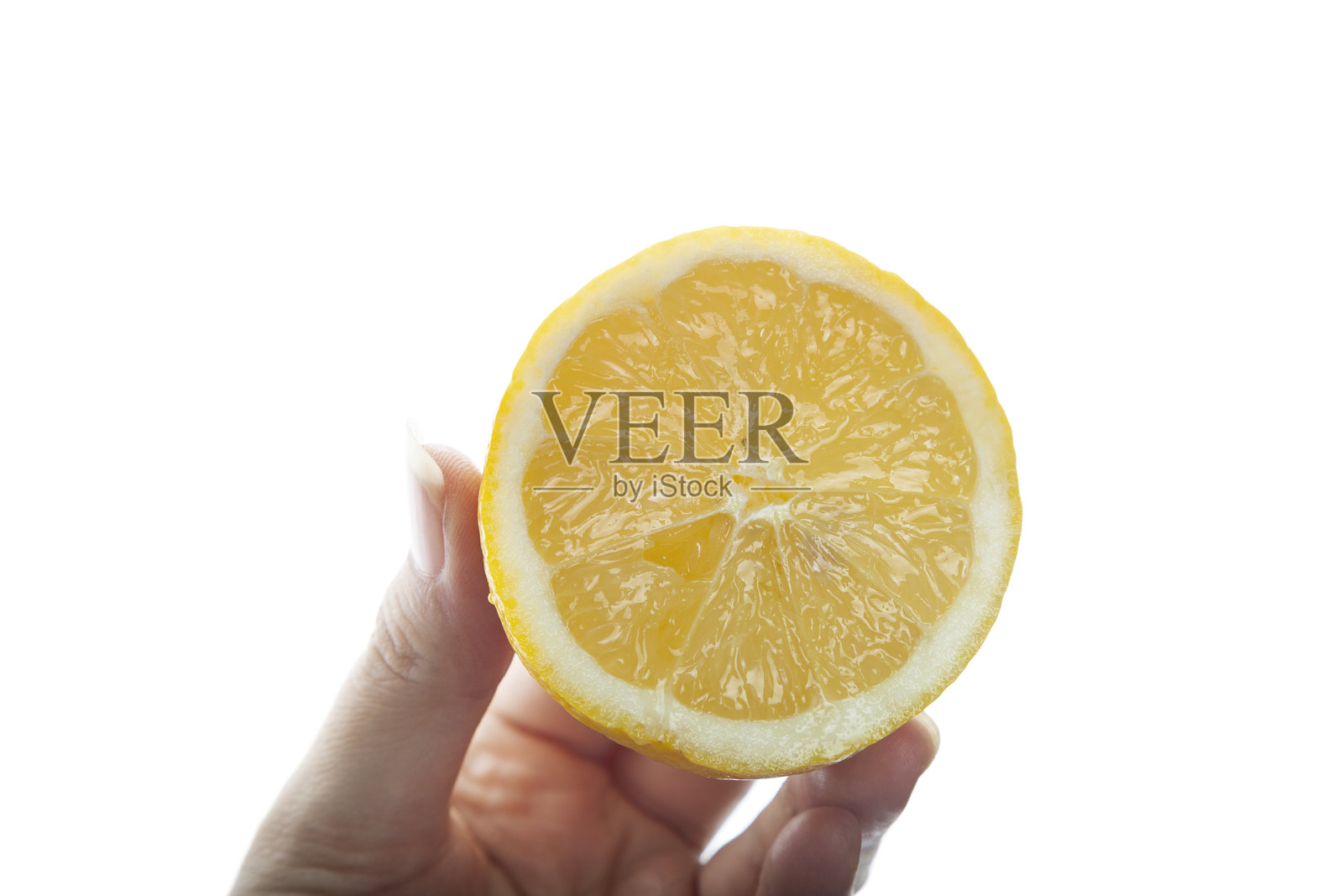 白底上，一只女性的手拿着一个切成两半的新鲜柠檬照片摄影图片