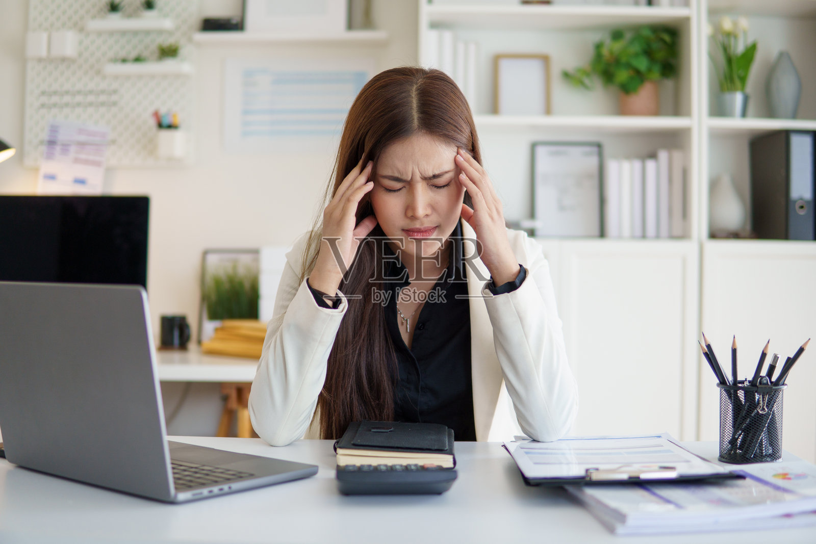 一名职业女性在办公室办公桌前工作，因压力而抱着头。照片摄影图片