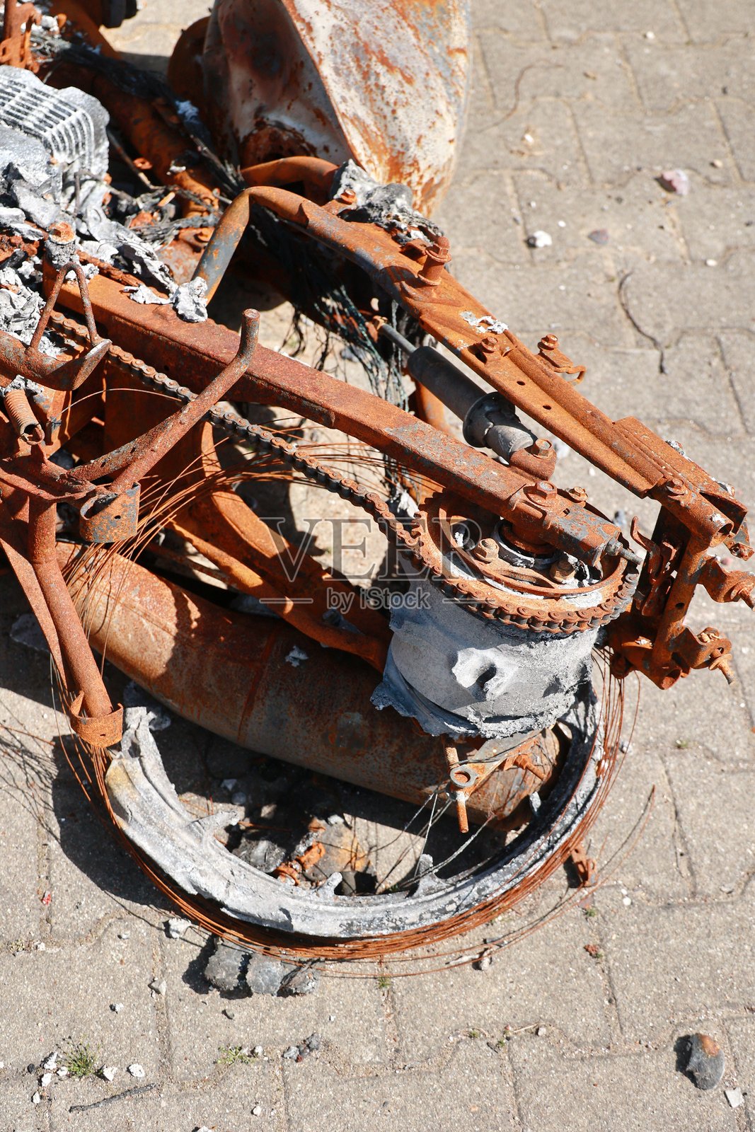 一辆生锈的摩托车倒在地上，缺少一条链条照片摄影图片