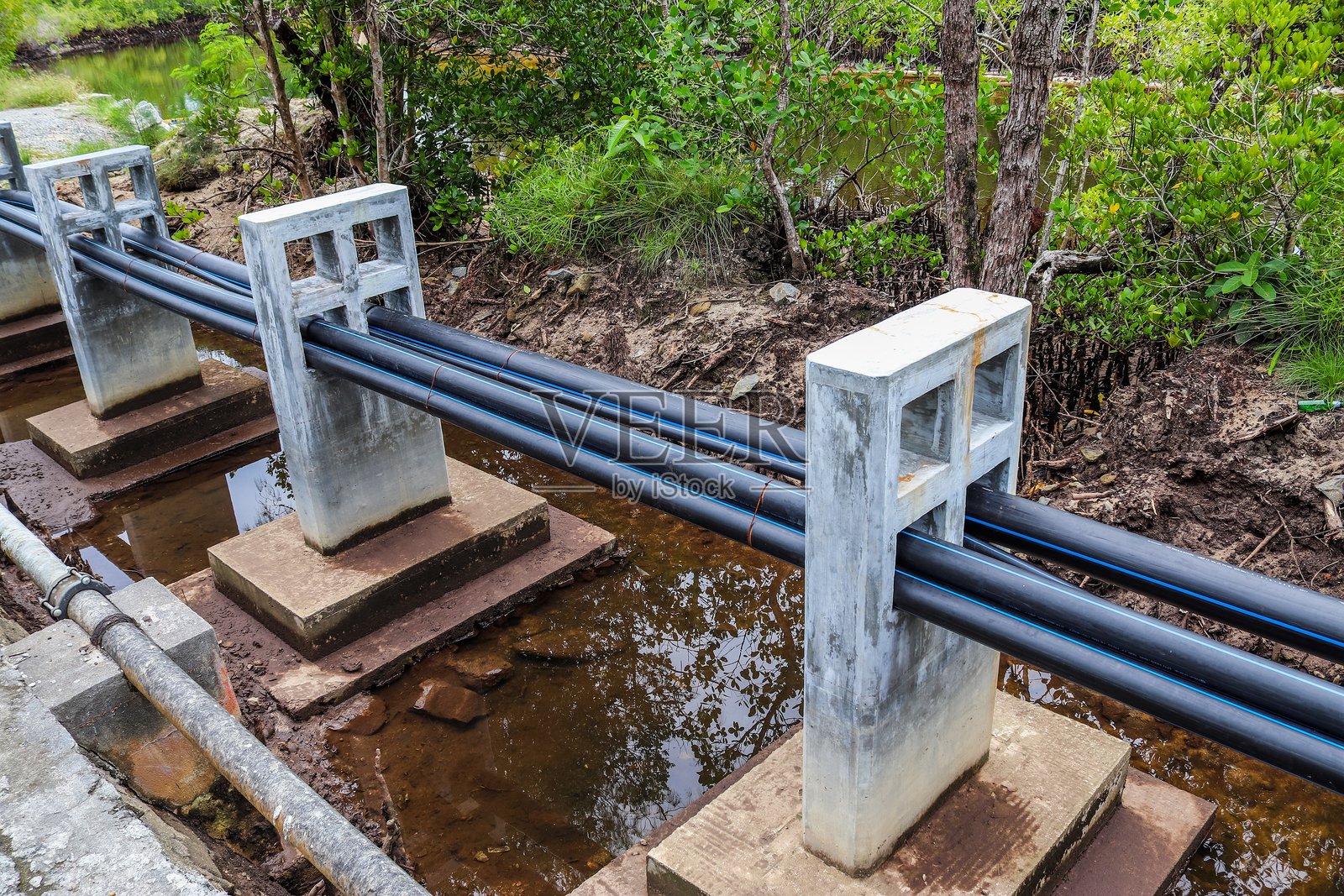 混凝土支撑架上的水管跨越溪流照片摄影图片