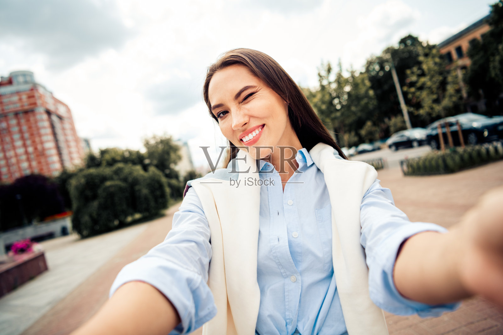 一位自信的年轻女子在阳光明媚的日子里，面带愉悦的表情，在城市环境中摆出姿势。照片摄影图片