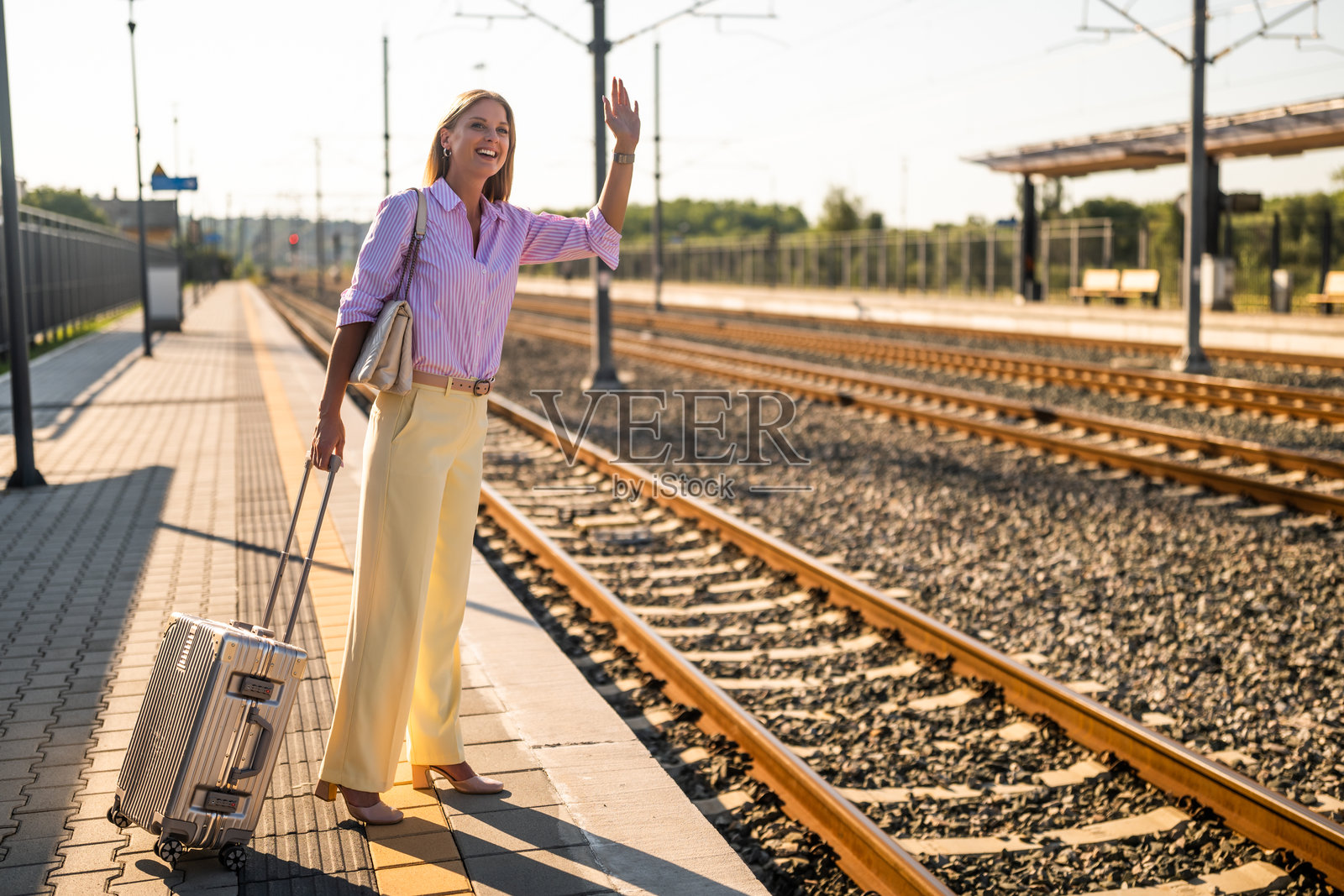 一位快乐的女商人在火车站挥手致意照片摄影图片
