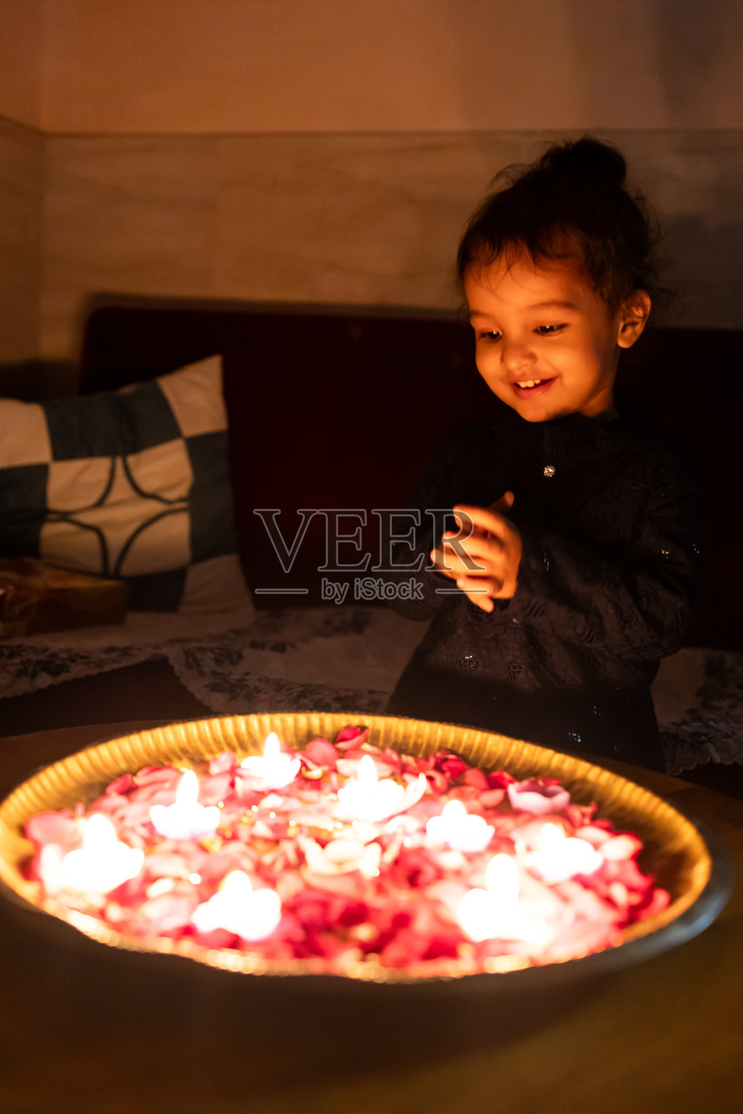 可爱的学步儿童在室内迪瓦利节上，手持电子蜡烛，兴奋不已照片摄影图片
