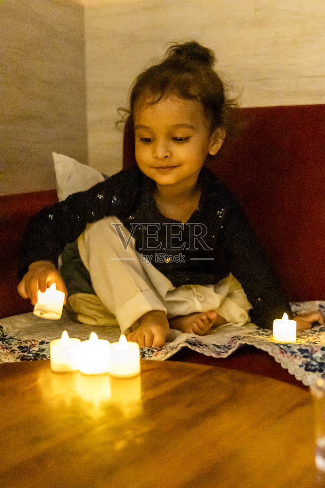 可爱的学步儿童在室内迪瓦利节用人造蜡烛兴奋地庆祝照片摄影图片