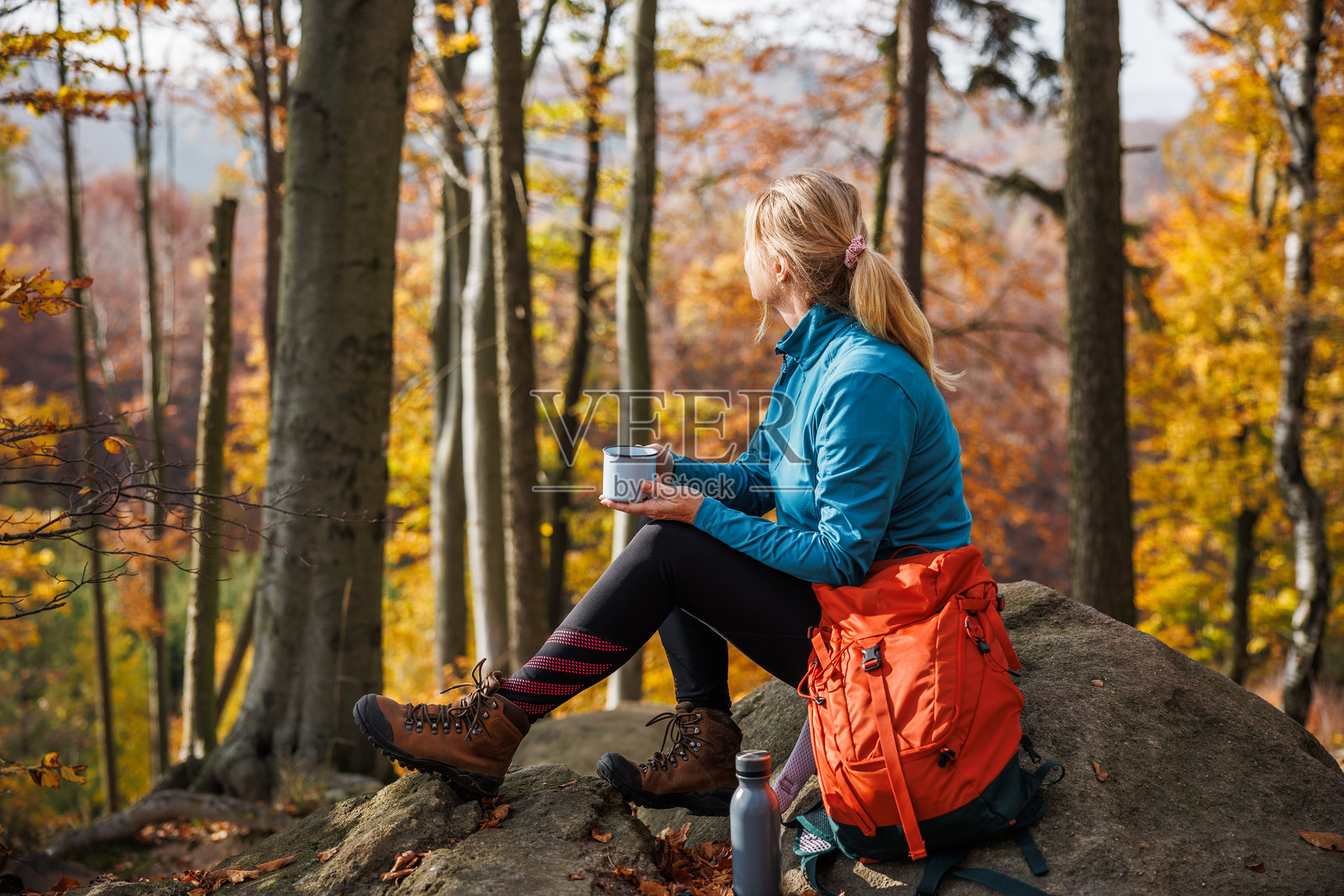 身着运动服的女性在秋季林地山峰成功徒步后休息照片摄影图片