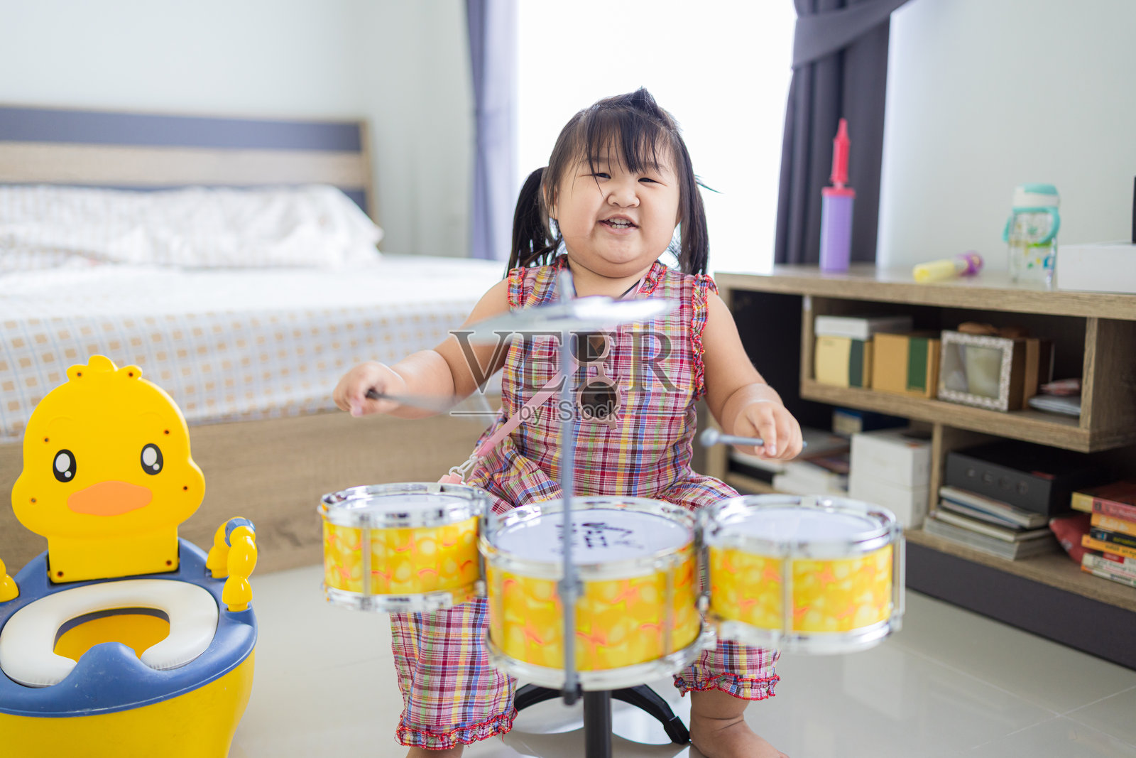 一个可爱的亚洲小女孩在家玩玩具鼓，玩得很开心照片摄影图片