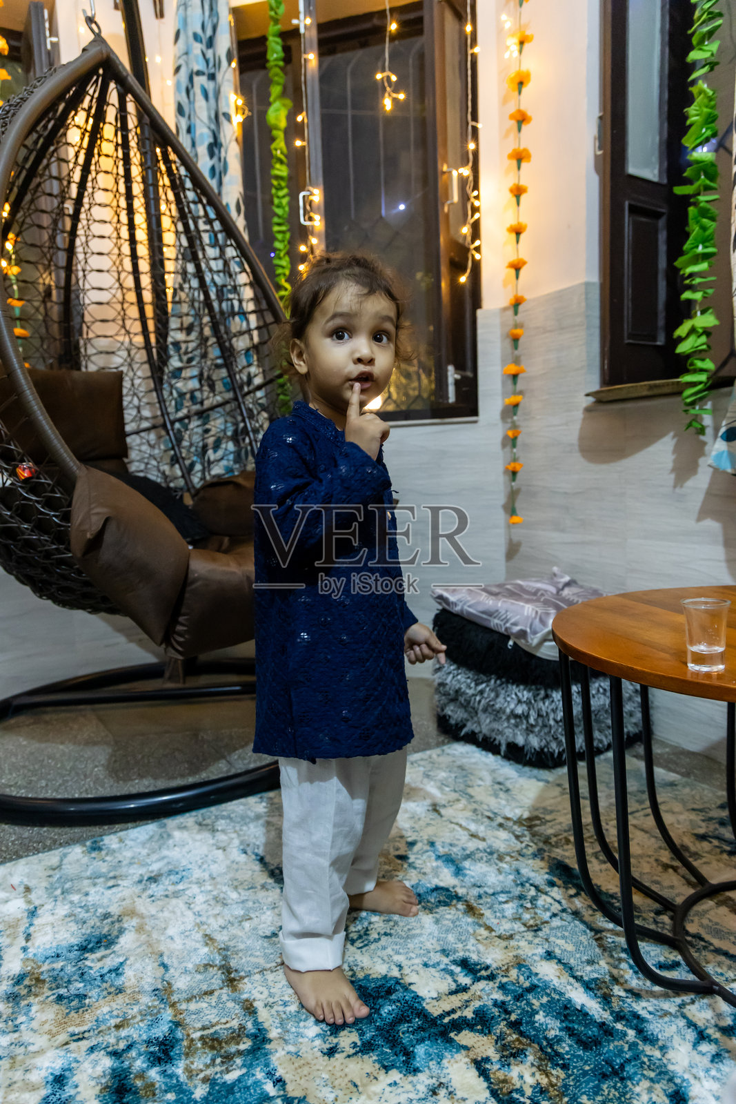 可爱的幼儿在排灯节上兴奋地手里拿着人造蜡烛，背景是家居装饰。照片摄影图片