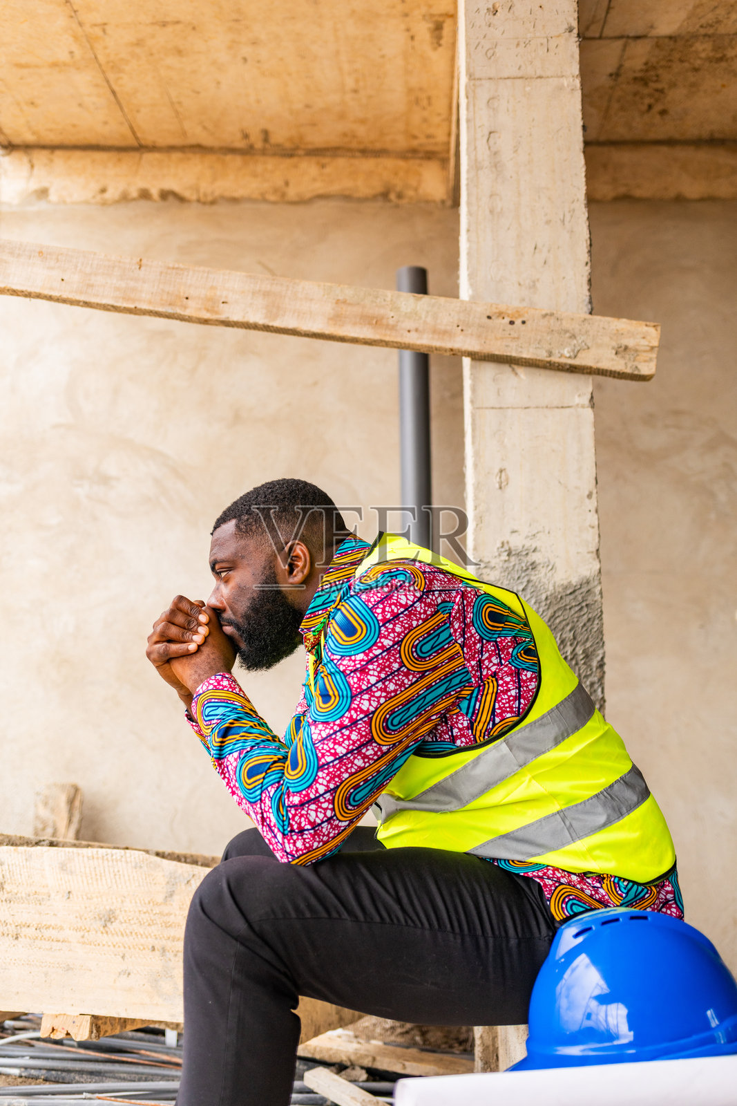 一位沮丧不知所措的非洲建筑工程师，在建筑工地上带着失望坐着，象征着建筑行业的挑战照片摄影图片