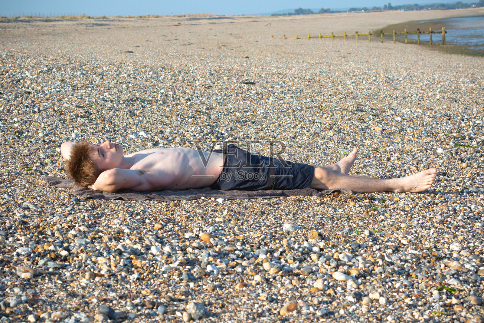 一个少年在海滩上晒日光浴照片摄影图片