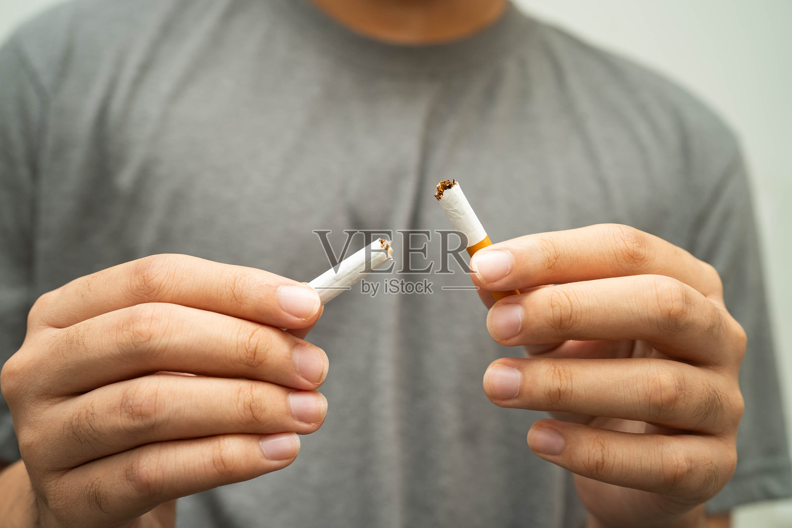 亚洲青少年男性戒烟，手中捏碎香烟。照片摄影图片