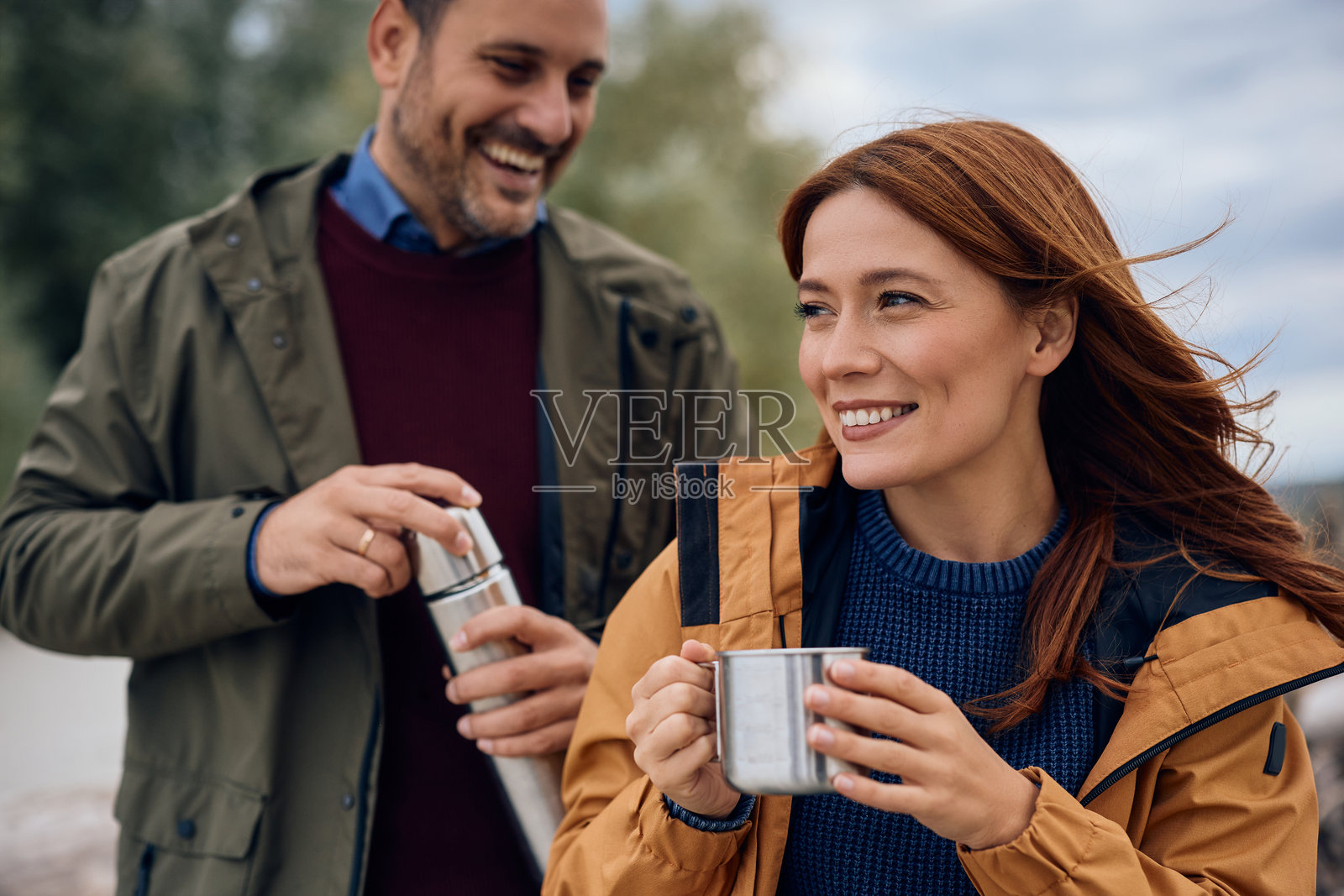 快乐的夫妇在户外度过秋日，一边喝茶。照片摄影图片