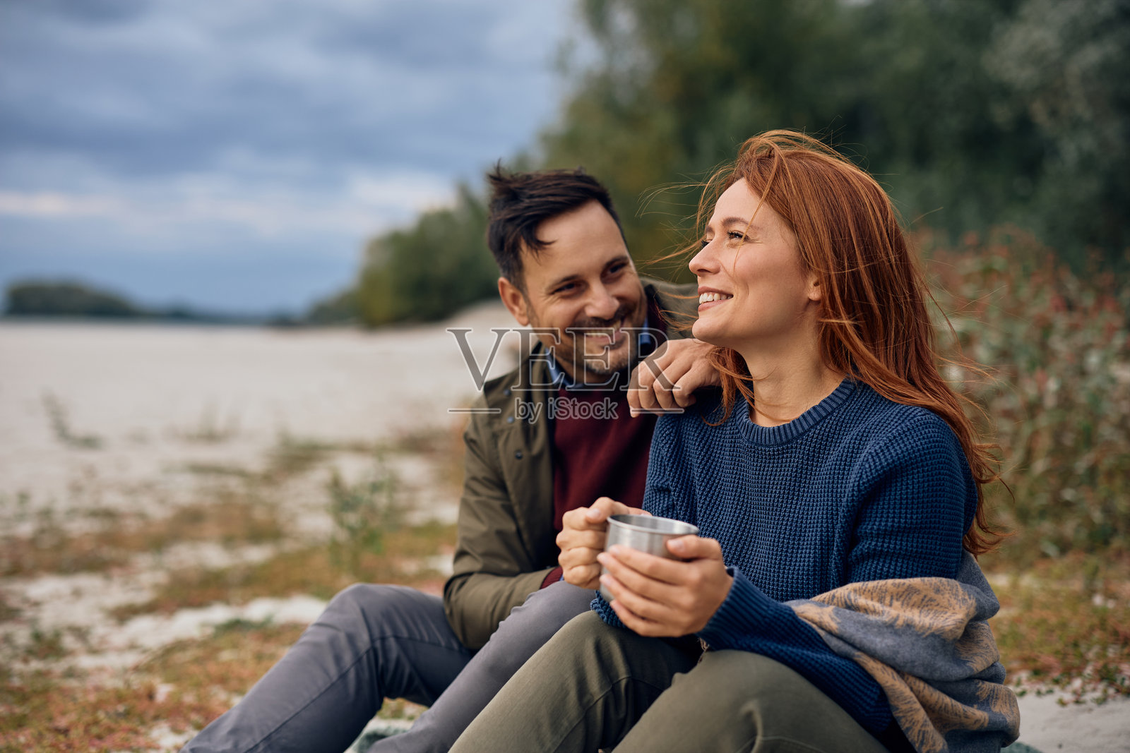 一对幸福的情侣在秋日暖阳下，于大自然中享用热茶。照片摄影图片