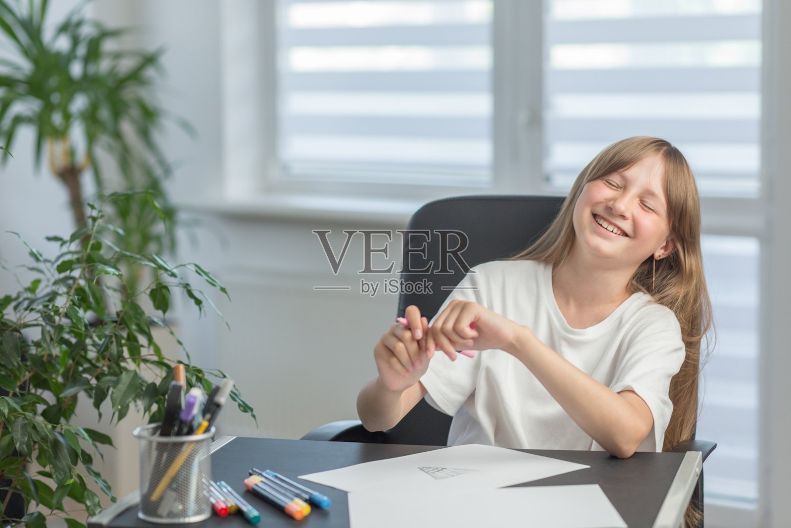 开心地在书桌前画画的女孩照片摄影图片