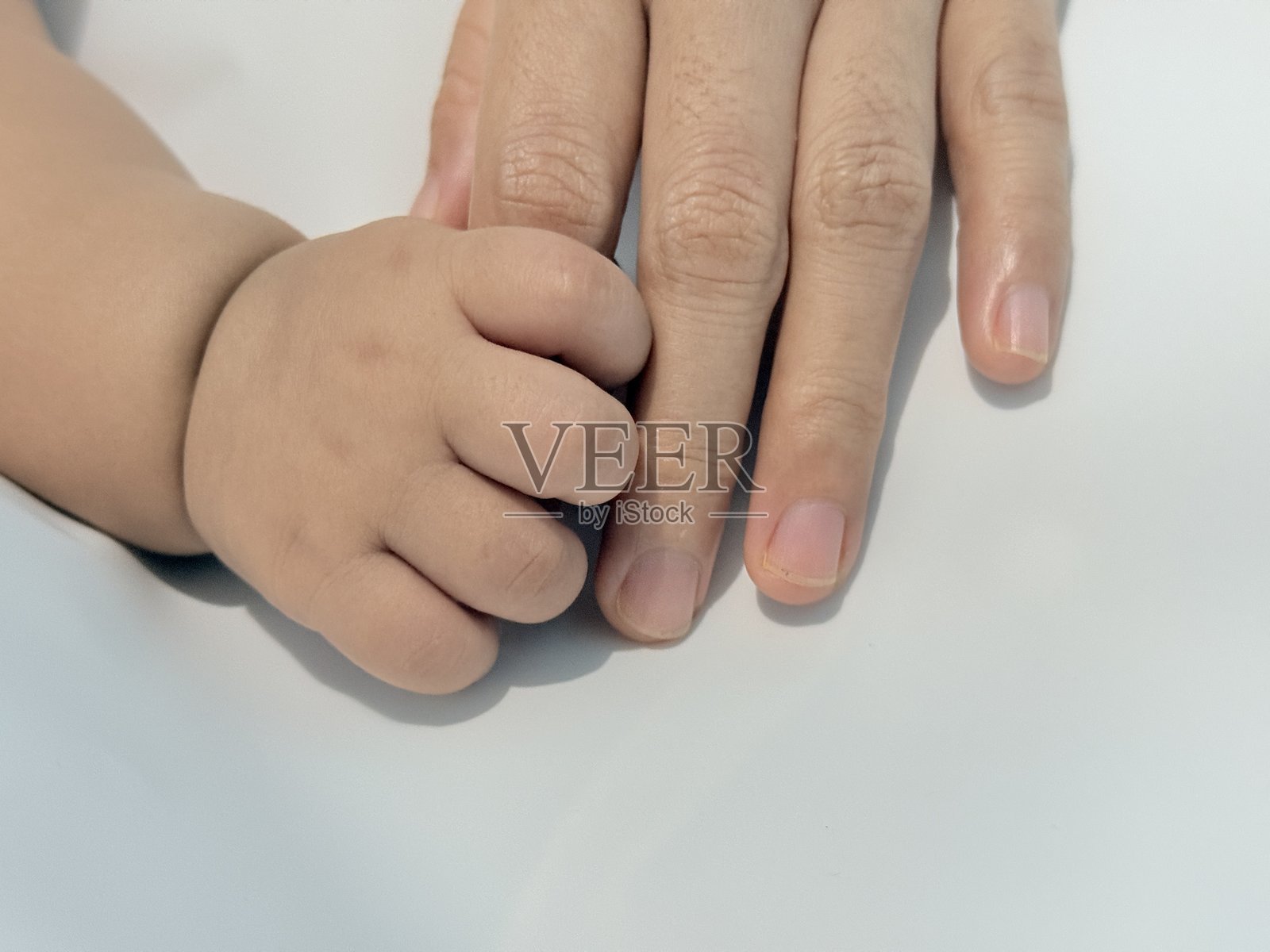 父母与婴儿手牵手，背景为柔软的白色照片摄影图片