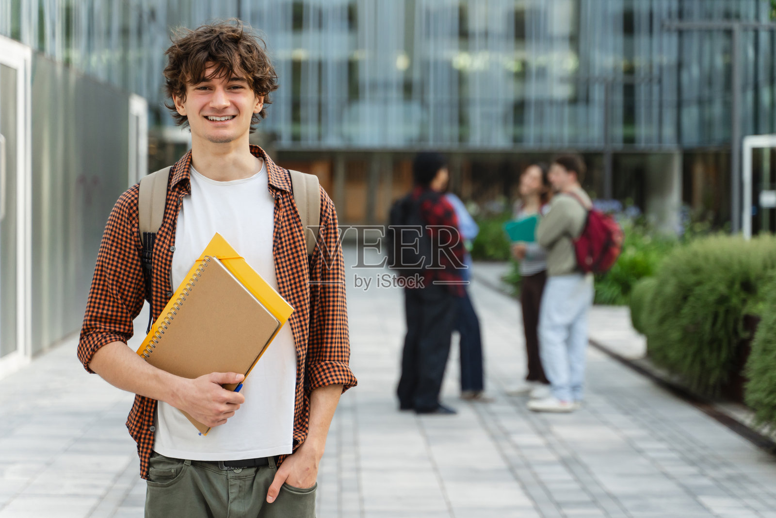 面带微笑的大学生站在校园里，开心地看着镜头，准备听讲座照片摄影图片