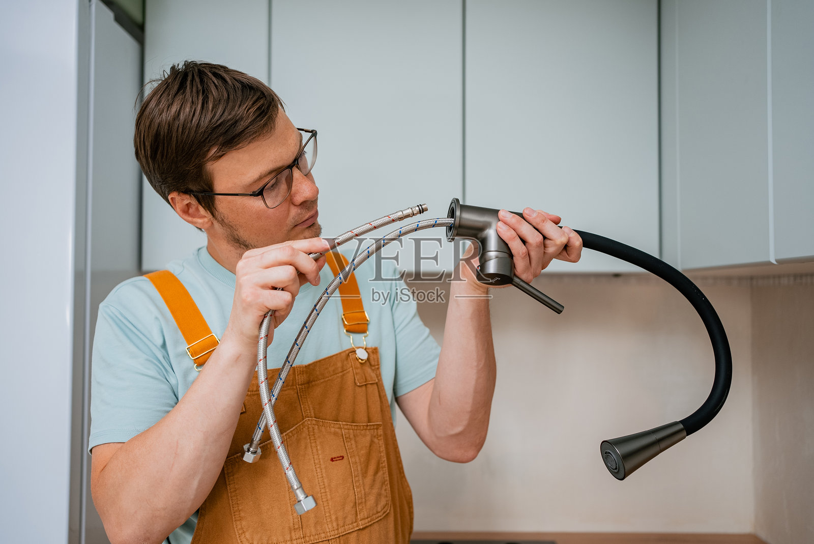 专业水管工将柔性供水管连接到现代厨房水龙头，进行精确安装以确保无泄漏的管道系统照片摄影图片