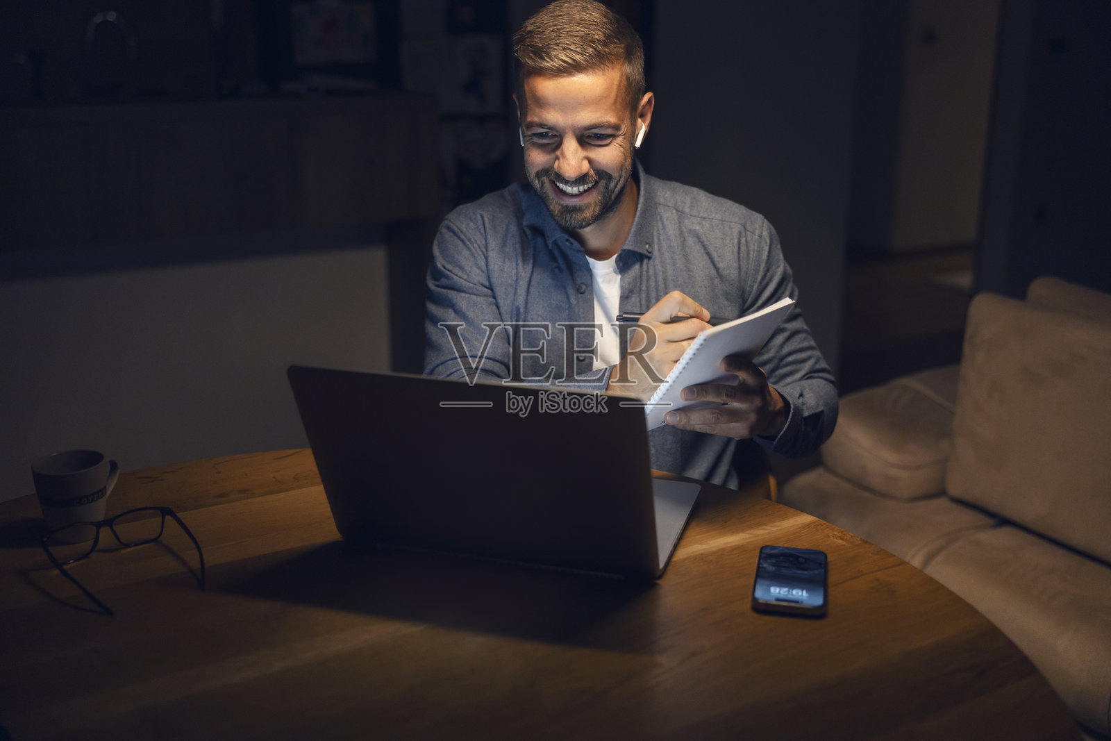 男人在家远程工作，晚上参加线上会议照片摄影图片