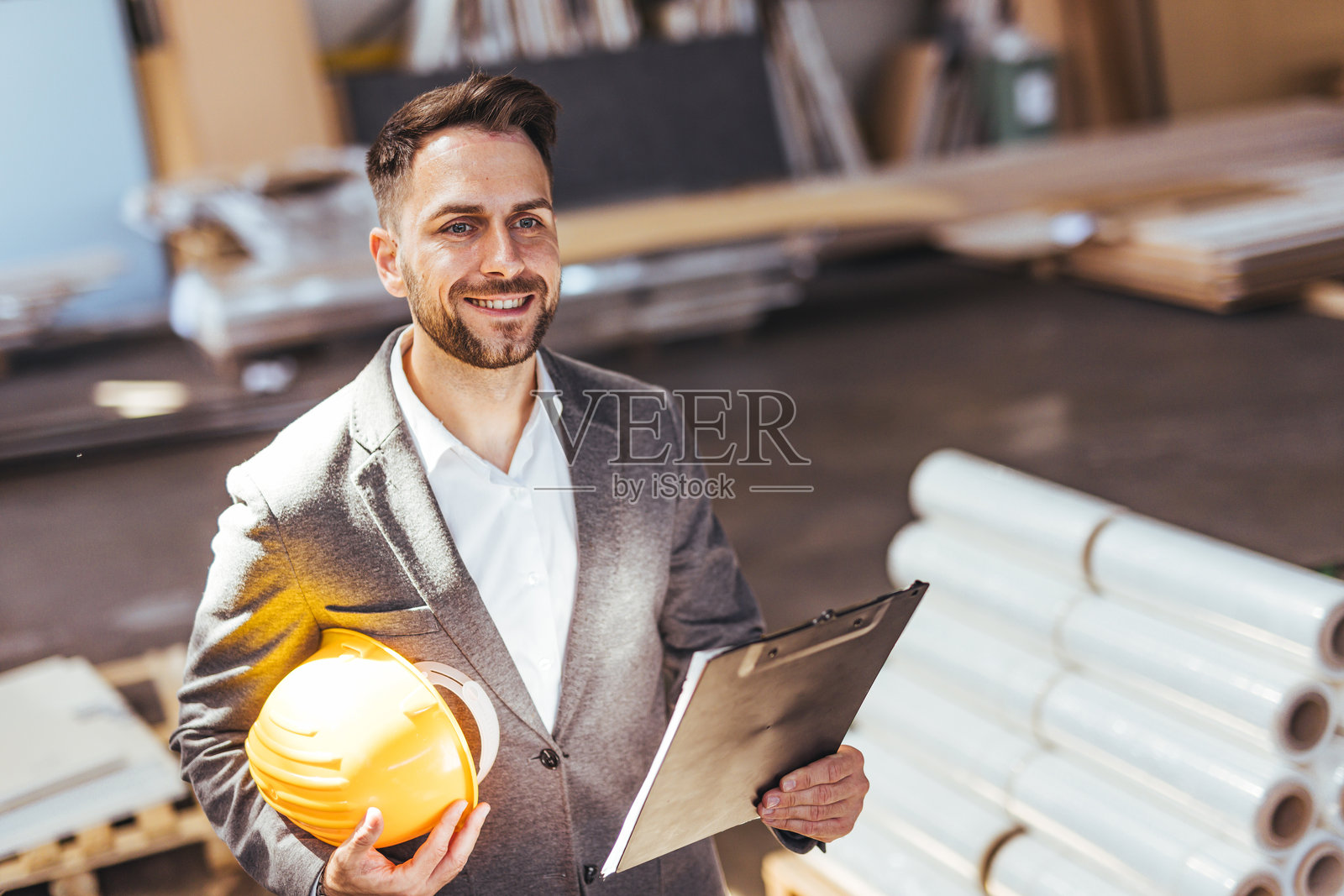 身着安全装备的专业人士在工业仓库环境中手持剪贴板照片摄影图片