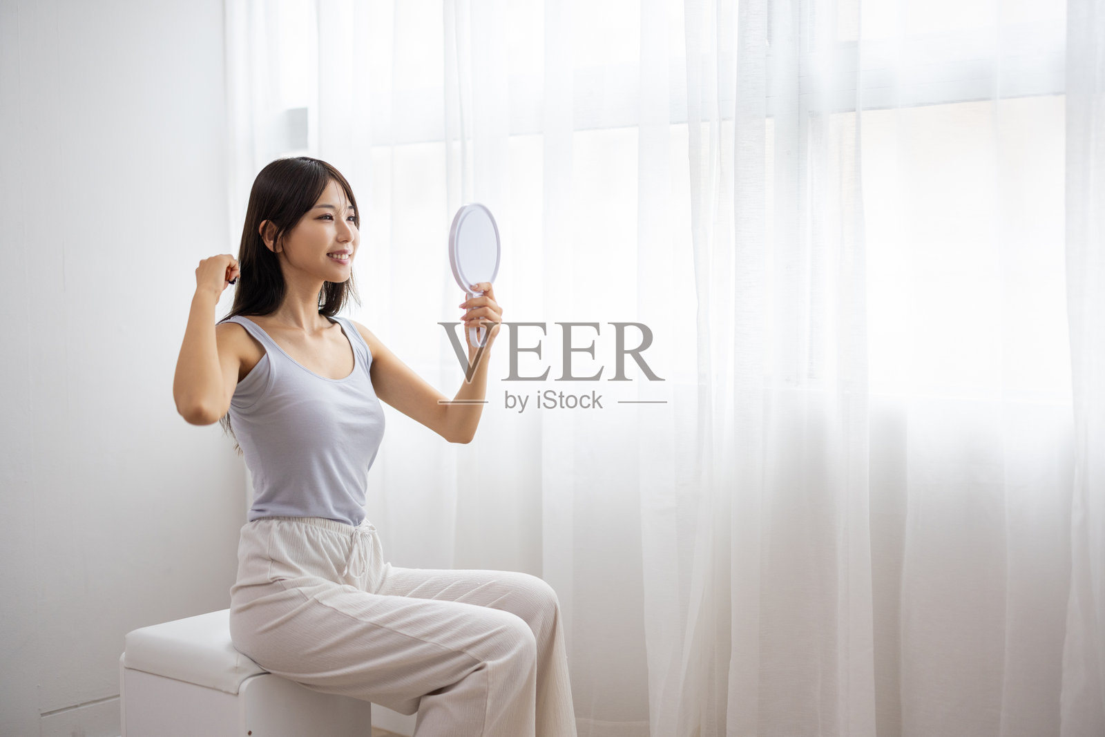 年轻女子手持镜子梳理头发照片摄影图片