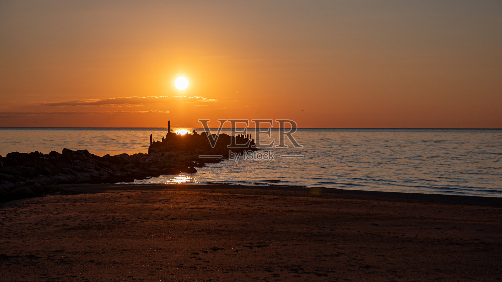 海边日落的魔法，古老的石码头，夕阳的最后一缕阳光映照在平静的海面上，特雅海滩，维泽梅海滨照片摄影图片