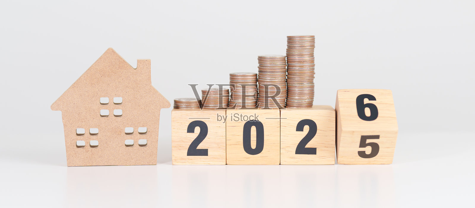 2025年末至2026年新年快乐，配有房屋模型和金币堆。房地产、房屋贷款、税务、投资、抵押贷款、金融、储蓄和新年决心概念照片摄影图片