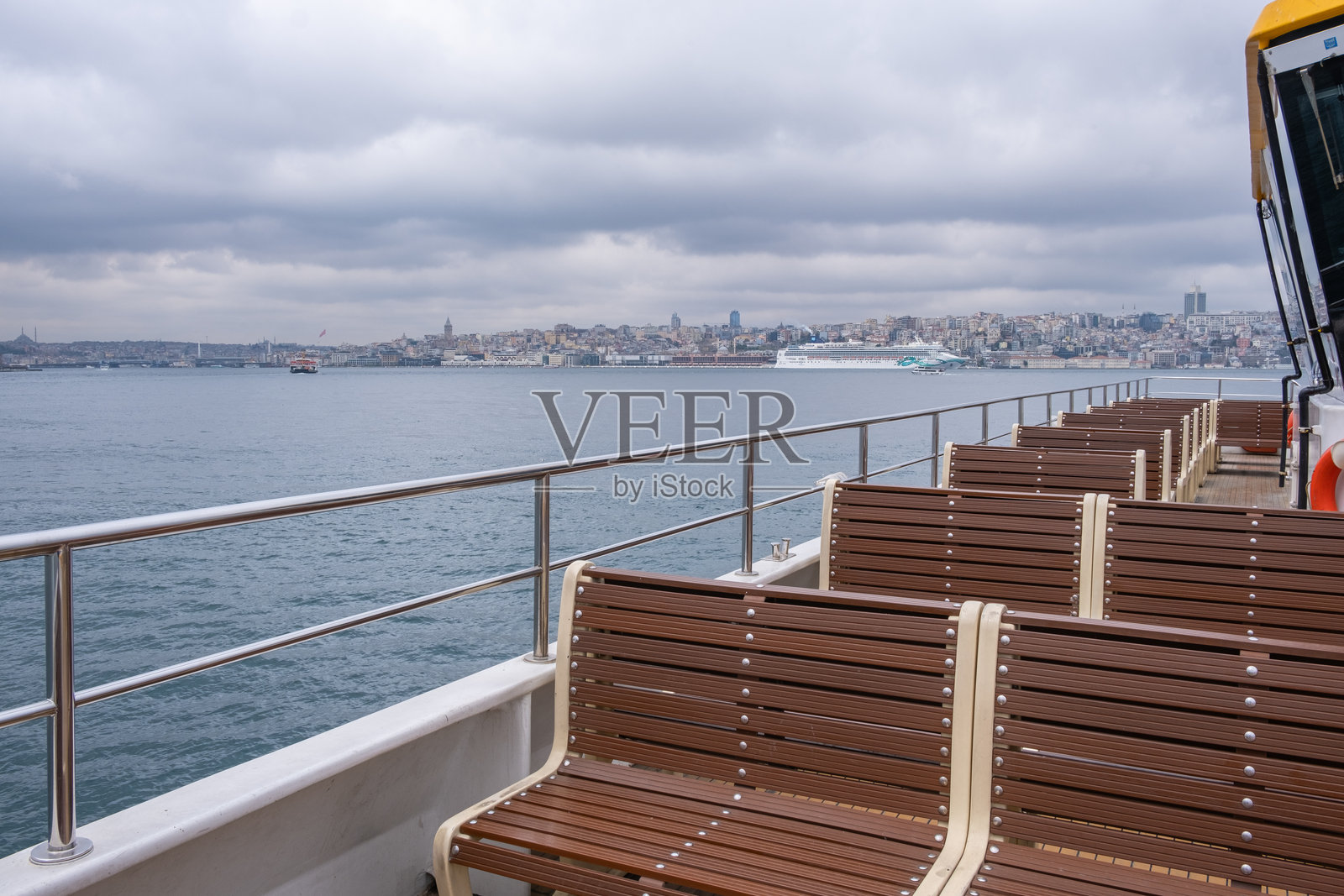 木制长椅在费里船的甲板上，背景是伊斯坦布尔市照片摄影图片
