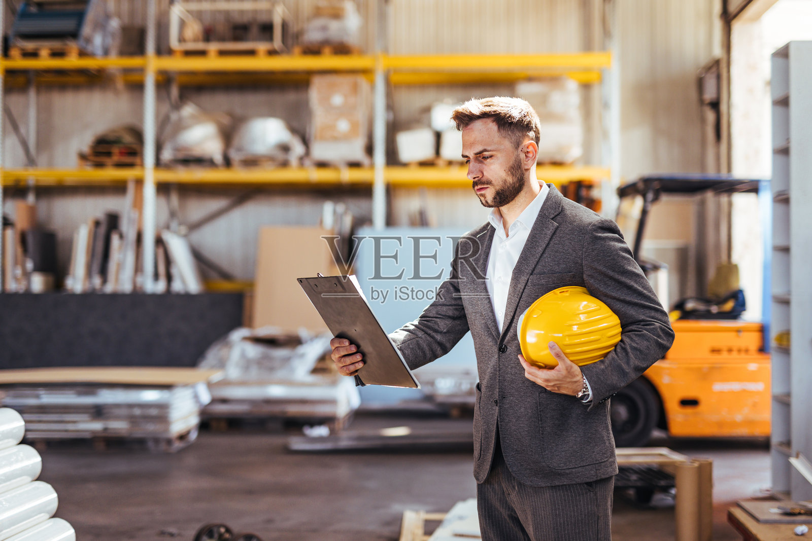 商务专业人士在仓库检查时手持黄色安全帽照片摄影图片