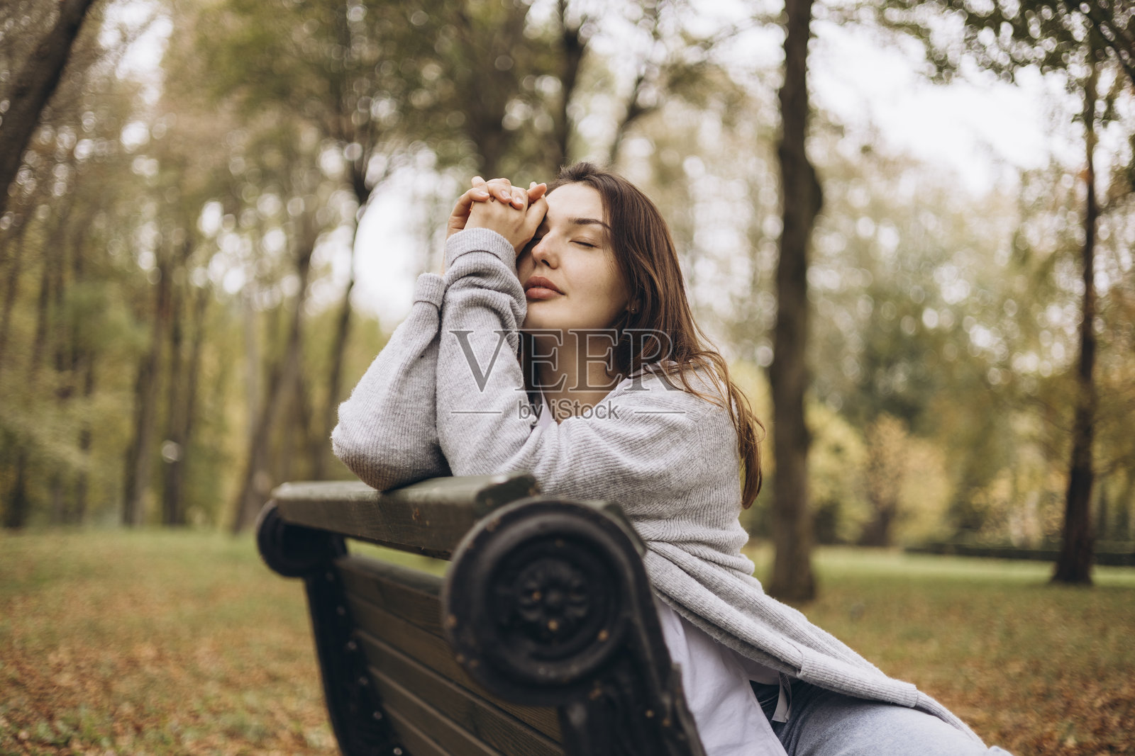 秋日公园长椅上放松的年轻女子肖像。照片摄影图片