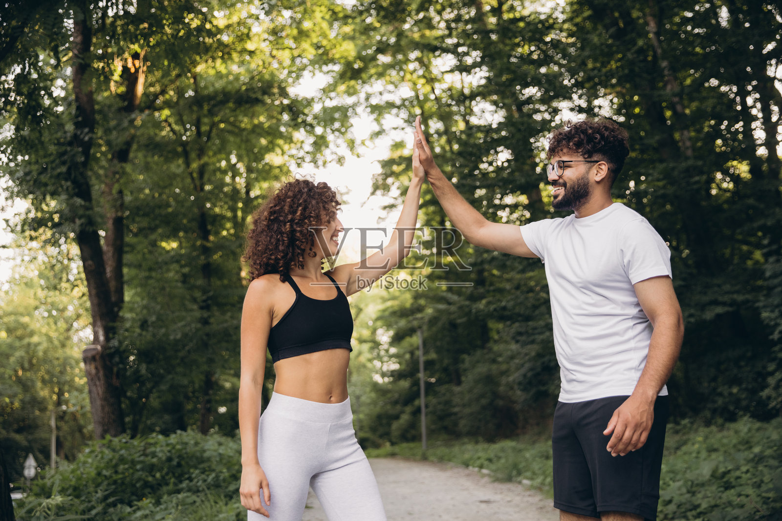 快乐的多民族情侣在公园锻炼后击掌庆祝照片摄影图片