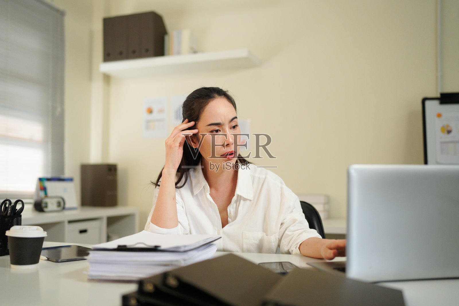 一位担心的、疲惫的、年长的女商人因头痛而在工作中。一位疲惫、沮丧、忙碌的四十多岁中年女商人在办公室感到压力，遇到了问题。照片摄影图片