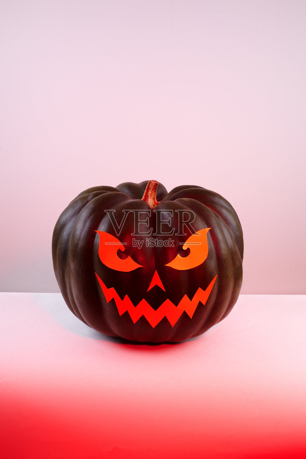 万圣节南瓜，纸雕惊悚面孔，在流行的红光下。杰克万圣节。笑脸杰克南瓜。照片摄影图片