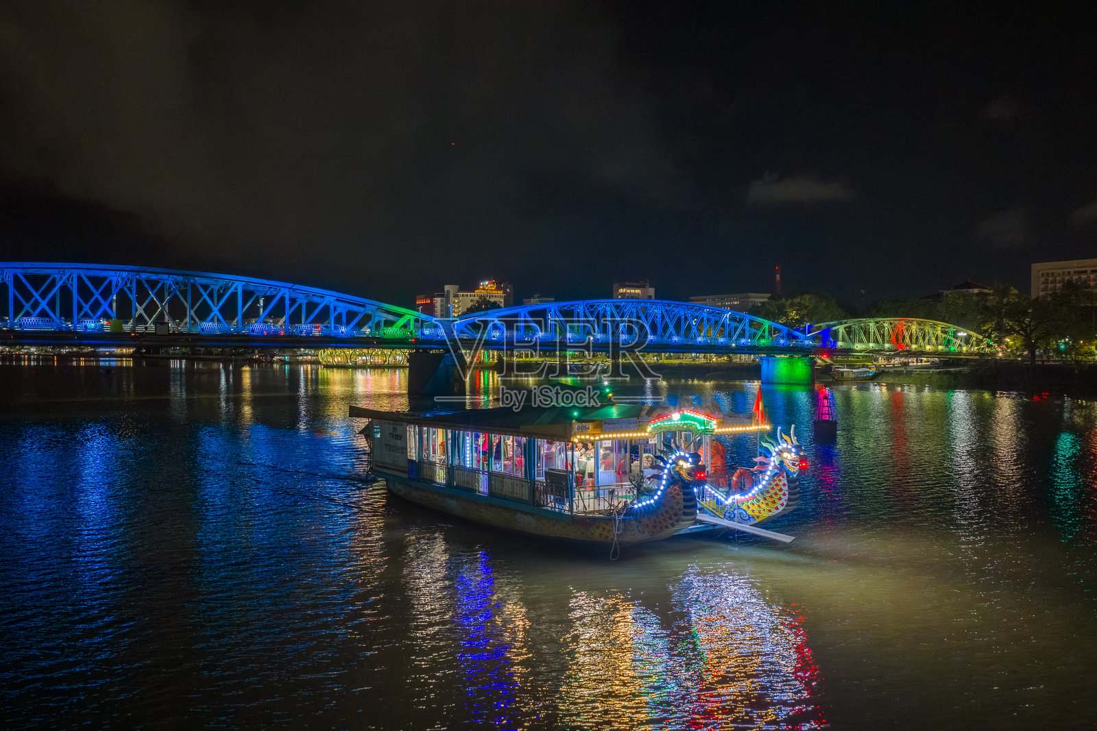 夜幕下的顺化市长钱桥全景。桥梁通体被照亮，水面有模糊的倒影。照片摄影图片