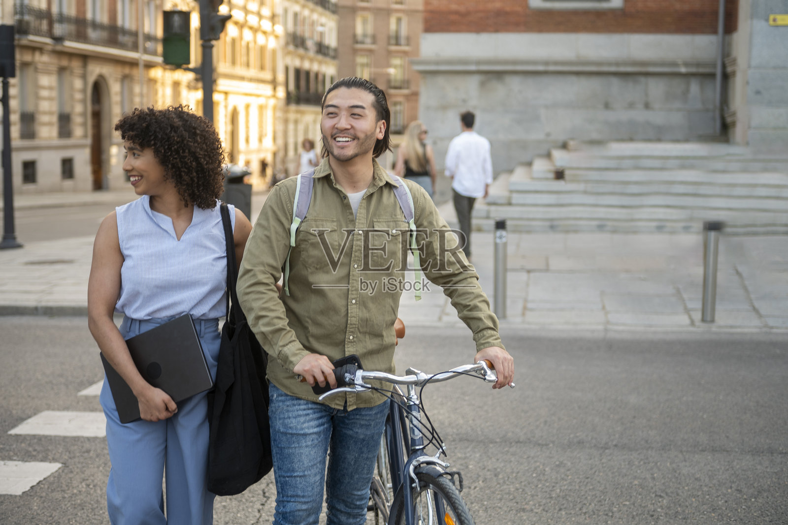 快乐的跨种族情侣在城市里骑自行车散步照片摄影图片