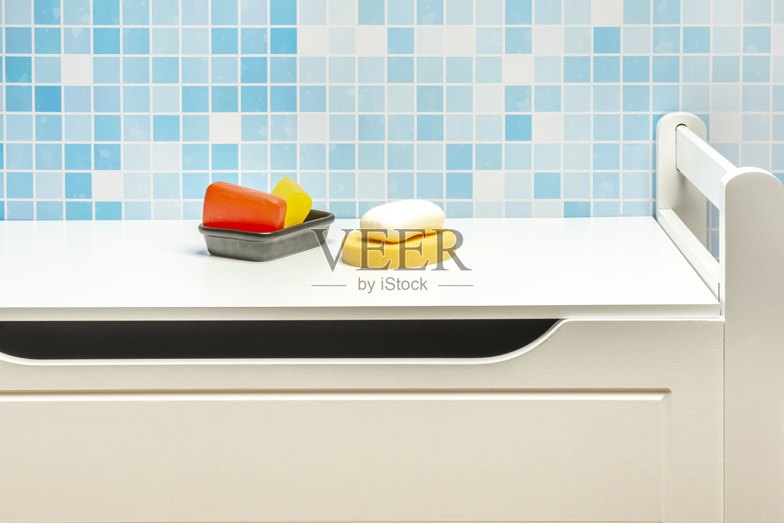 黑瓷碗里放着几块甘油皂，一块白色肥皂放在黄色海绵上，所有物品都放在白色橱柜上照片摄影图片