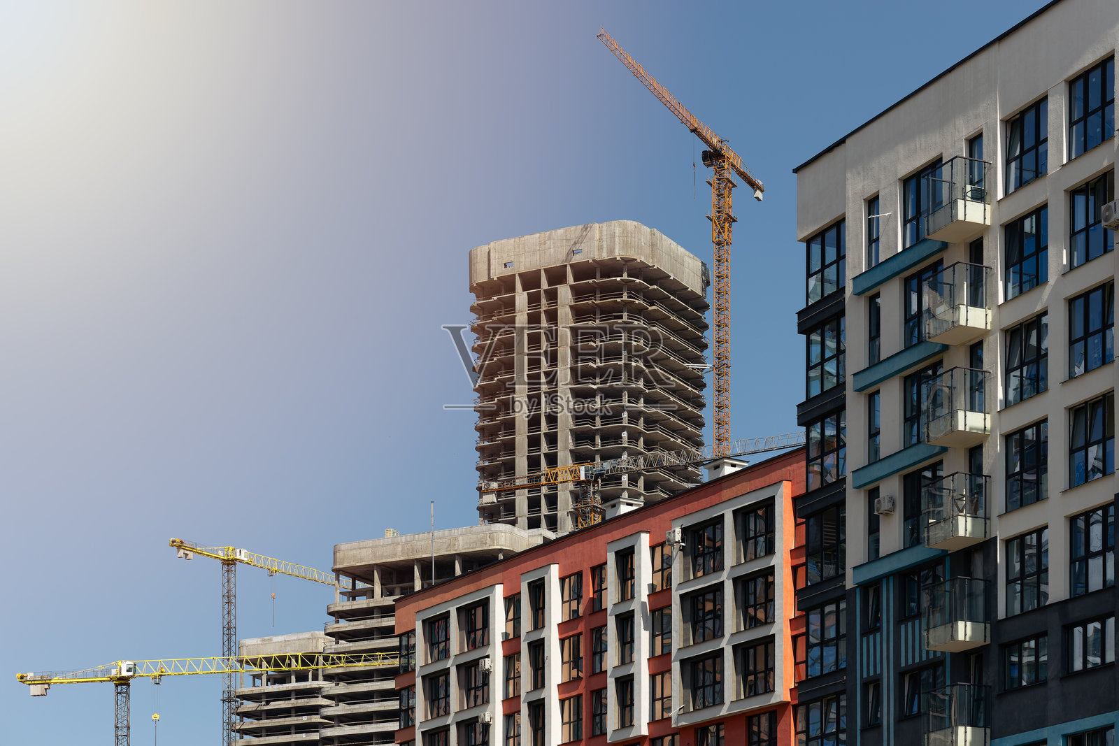 阳光明媚的城市背景下正在开发的高层建筑。现代住宅和商业综合体，设有照片摄影图片