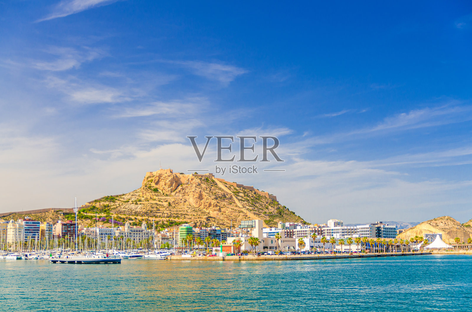 西班牙阿利坎特老城历史中心，包括阿利坎特港、港口、海港、船只，以及本纳坎蒂尔山上的圣巴巴拉城堡，地中海水域。照片摄影图片