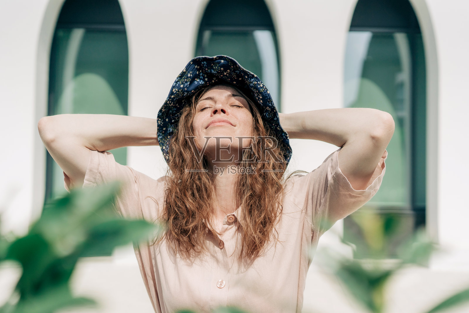 一位戴着花纹帽子的年轻女子夏天在户外站着。照片摄影图片