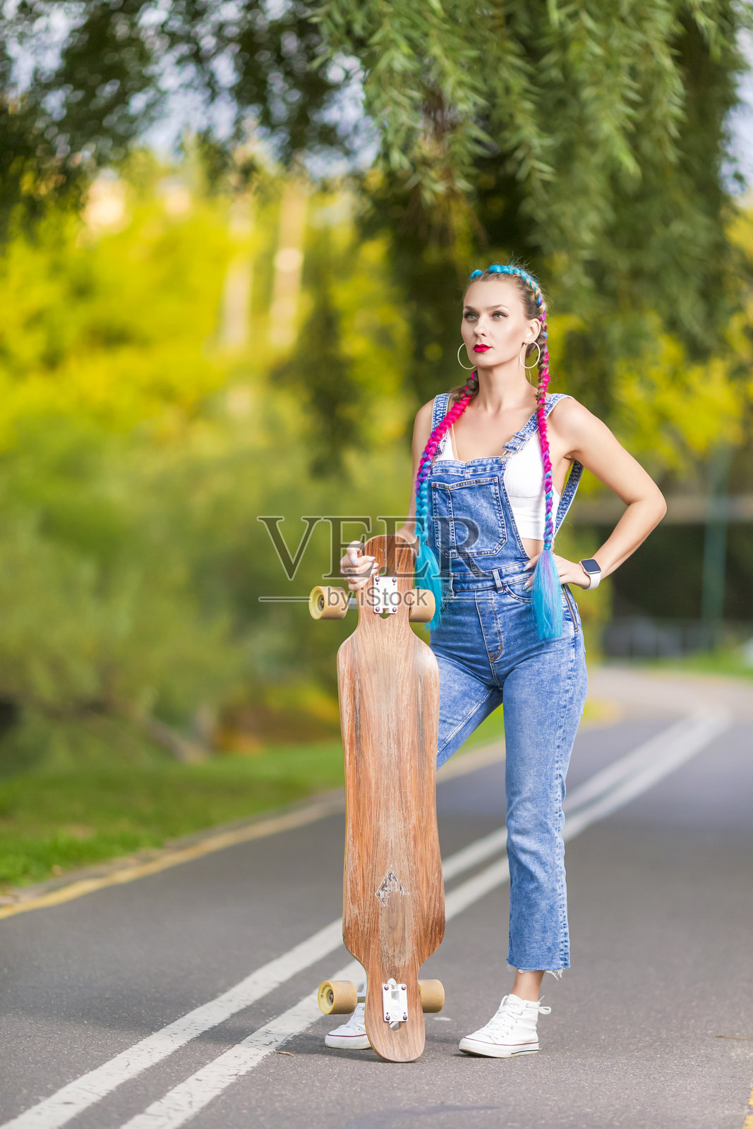 青春生活。可爱迷人的时尚滑板女孩，长板，在路上摆姿势。照片摄影图片