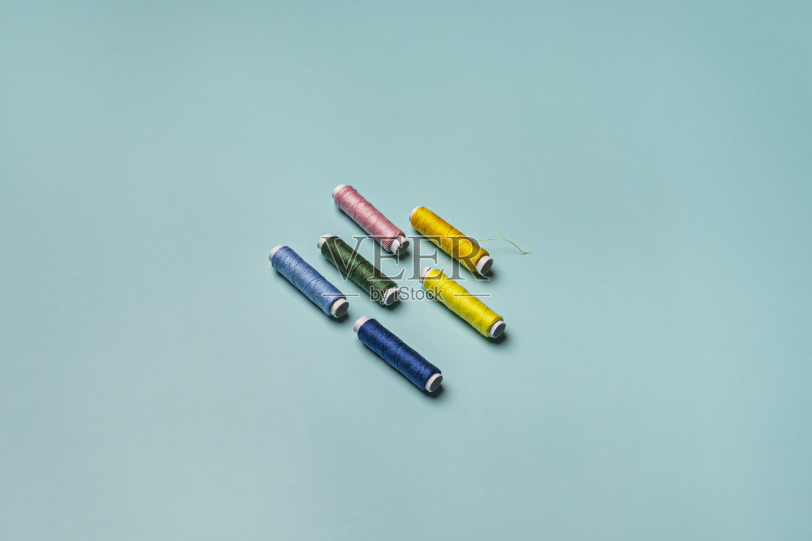 光滑的蓝色表面上有彩色线轴正在进行缝纫修补照片摄影图片