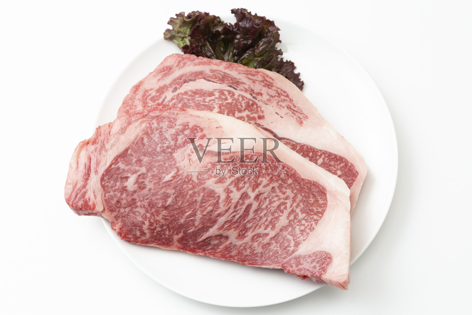 白盘子里的牛排，白色背景照片摄影图片
