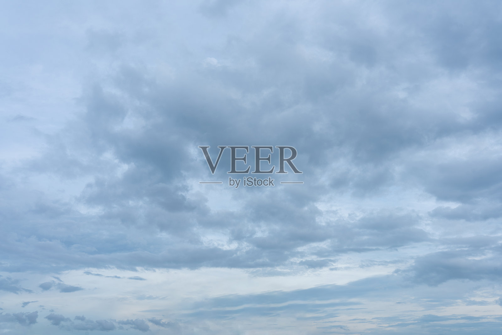 地平线上方是阴沉的天空，层层叠叠的积云呈现出柔和的蓝色和灰色。照片摄影图片