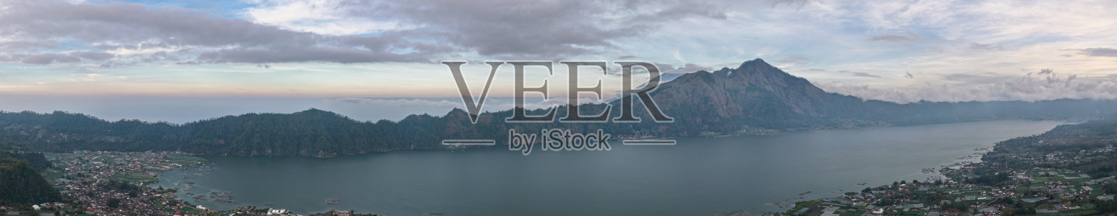 美丽的火山景观，平静的水面倒映着远处的山坡，天空晴朗，白云朵朵，位于巴厘岛金巴兰照片摄影图片